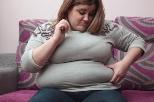 woman sitting on the couch touching her belly fat